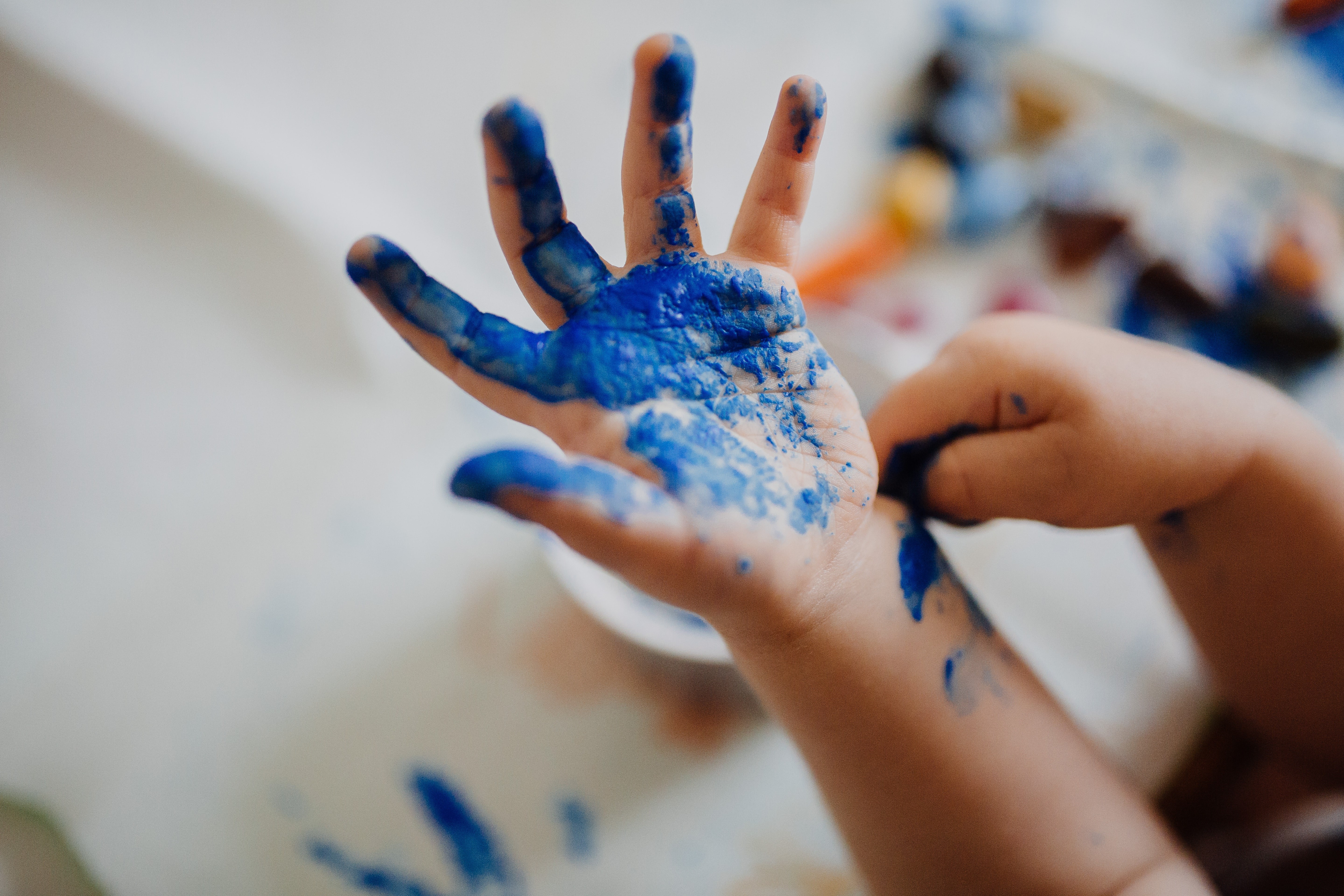 Bilden visar en barnhand med blå målarfärg på
