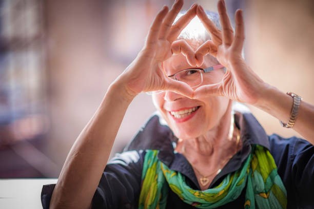 En äldre kvinna formar ett hjärta med sina händer