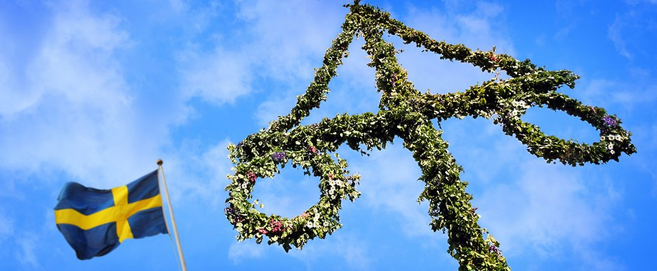 Bilden visar en midsommarstång bredvid den svenska flaggan