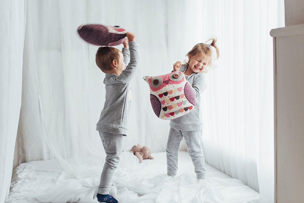 Två små barn leker kuddkrig