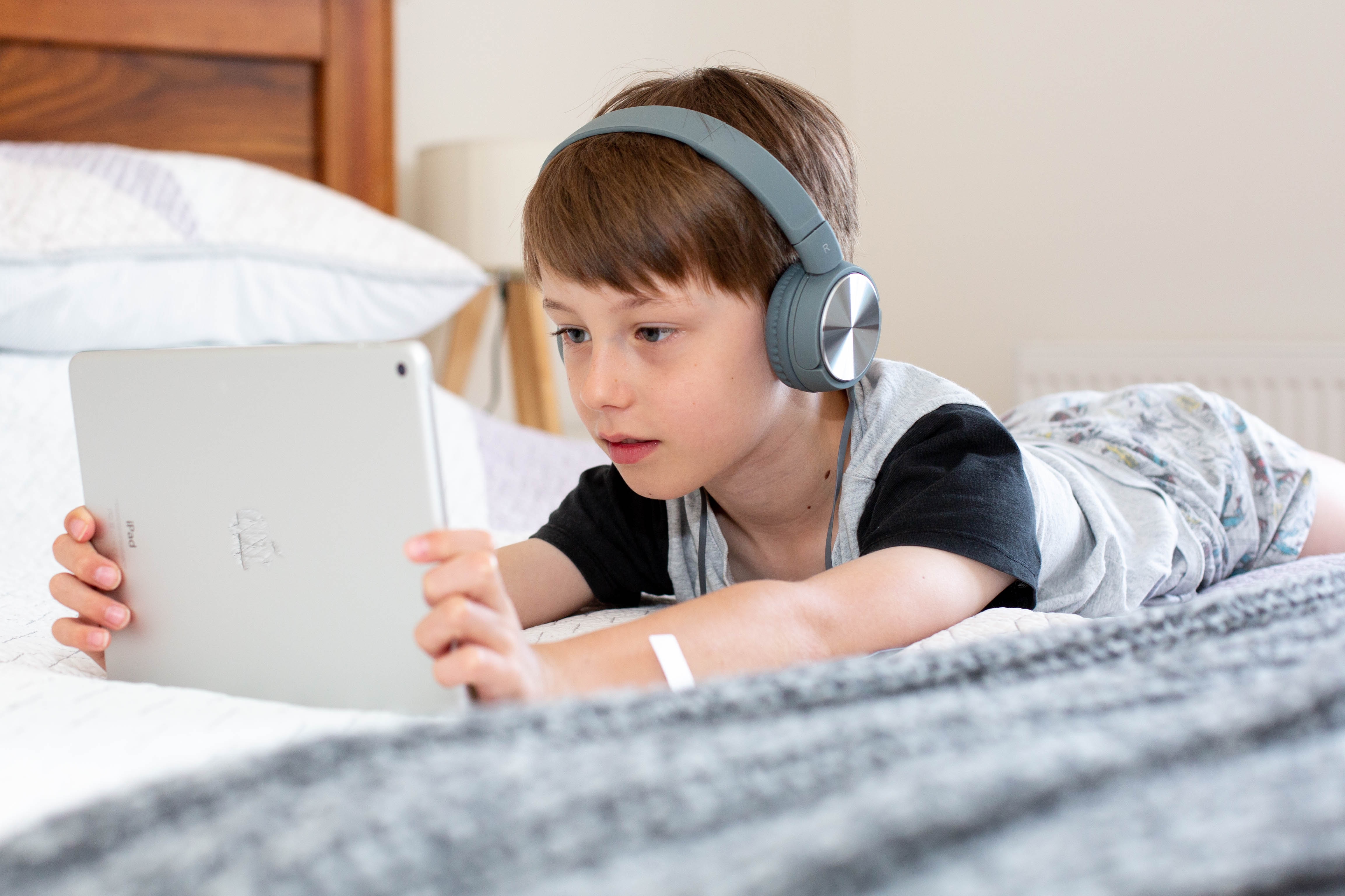 En ung kille ligger på sängen och kollar på sin Ipad