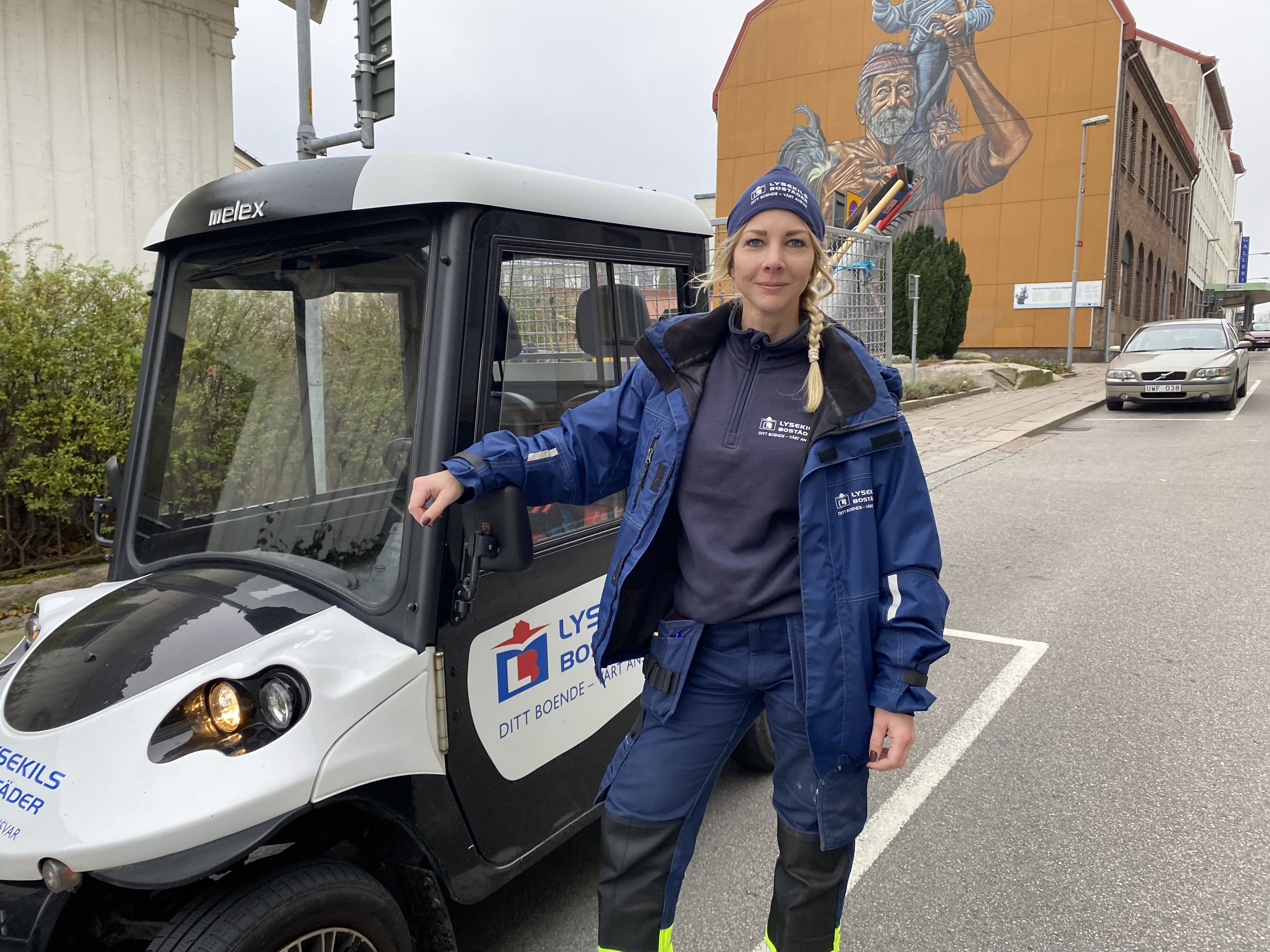 Vår nya fastighetsskötare Elna står på gatan framför sin elbil