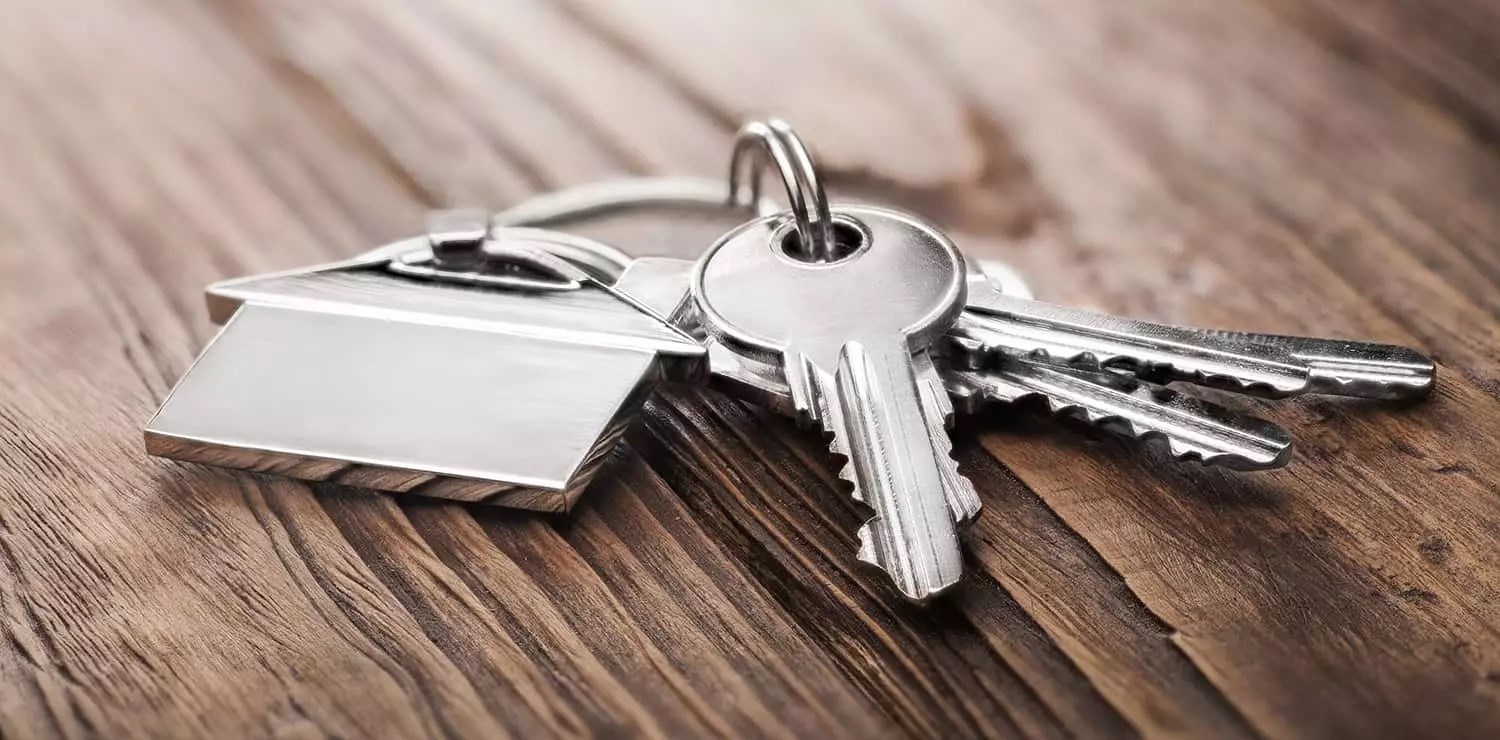 En nyckelknippa med en nyckelring i form av ett hus ligger på ett bord