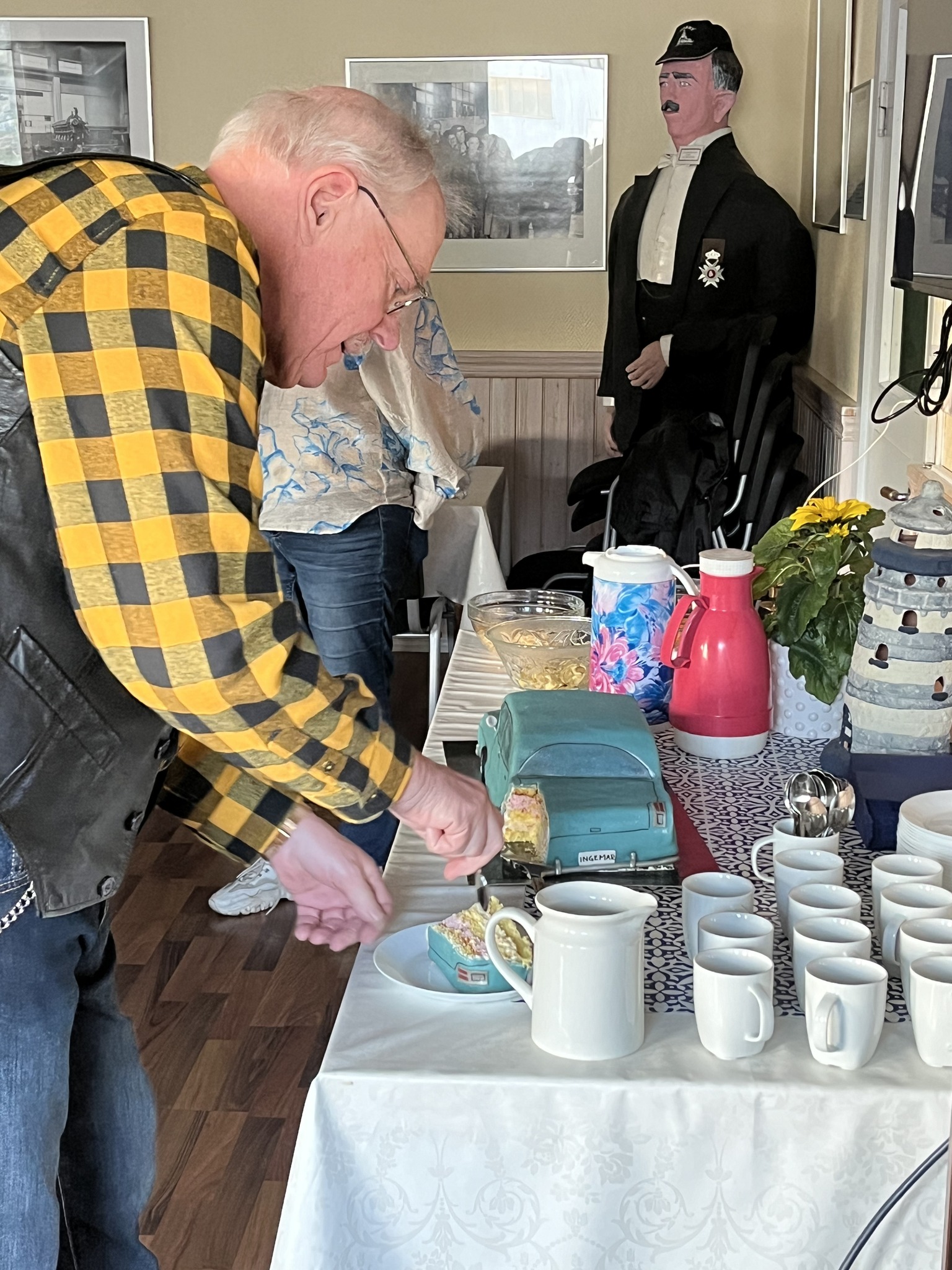 Ingemar Skarstedt skär en bit av en prinsesstårta. Tårtan avbildar en veteranbil.